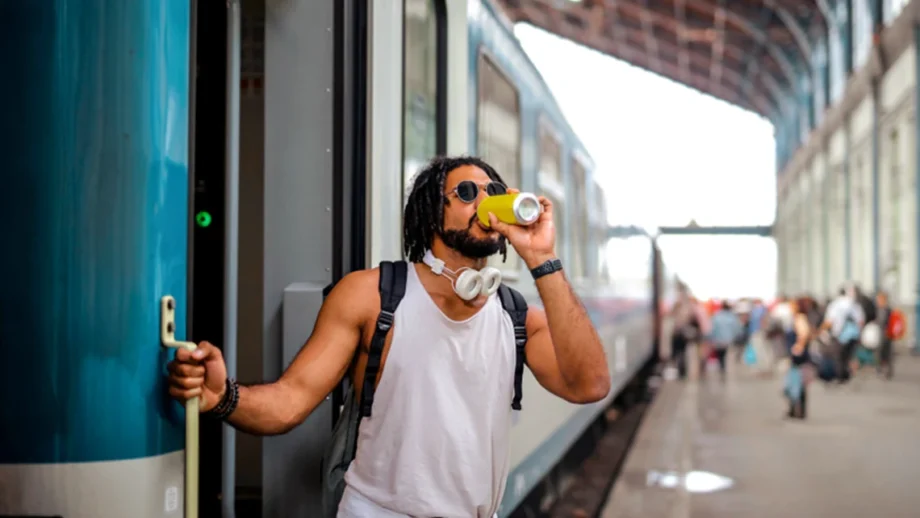Guy stepping out of a train while sipping a microdosing drink from a can