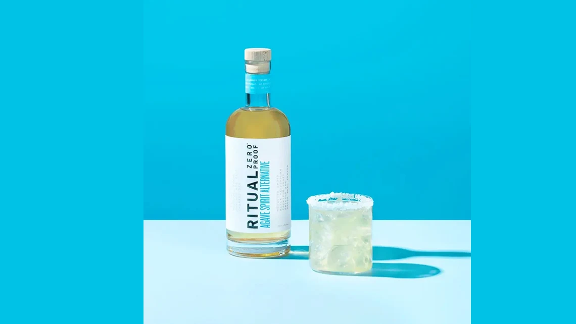 a glass rimmed with salt beside a bottle of Ritual Zero Proof Agave Spirit Alternative