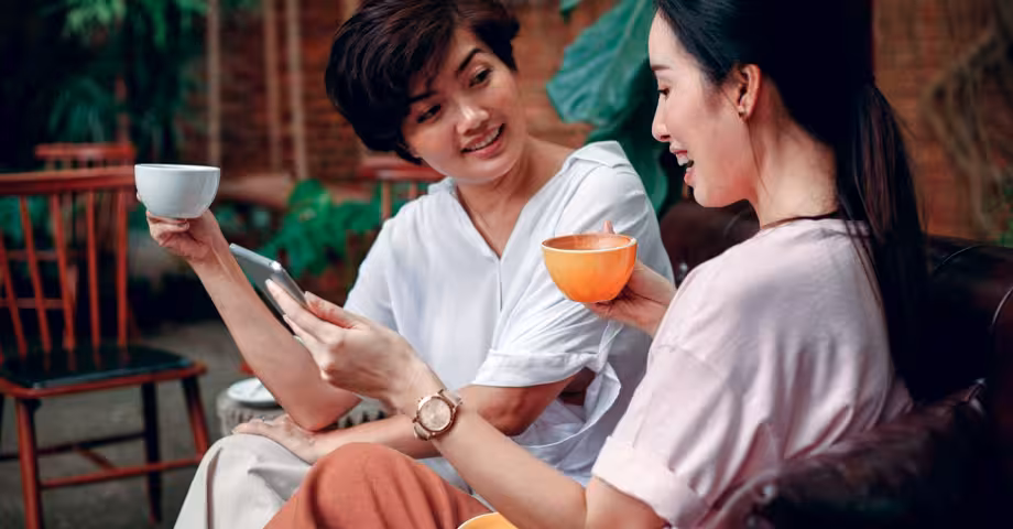 two Asian women drinking tea outdoors instead of alcohol while talking