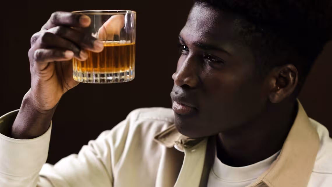 black man staring at glass he is holding